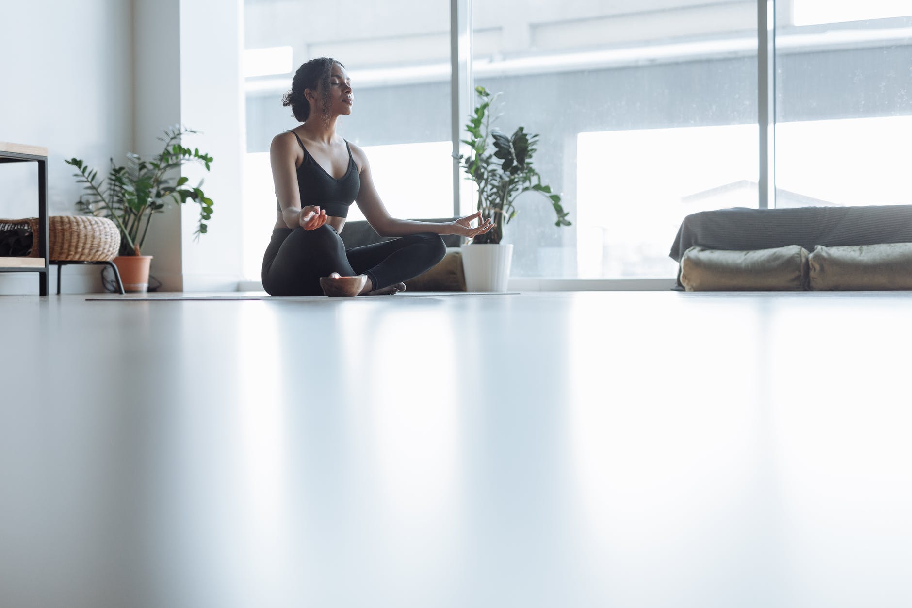 a woman in black active wear meditating at home